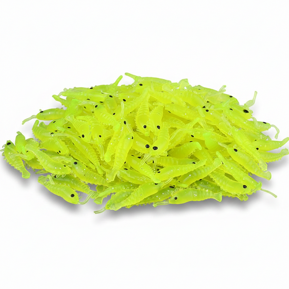 A pile of neon chartreuse green plastic fishing lures shaped like small shrimp or crawfish, with tiny black eyes, photographed on a clean white background.