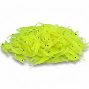 A pile of neon chartreuse green plastic fishing lures shaped like small shrimp or crawfish, with tiny black eyes, photographed on a clean white background.