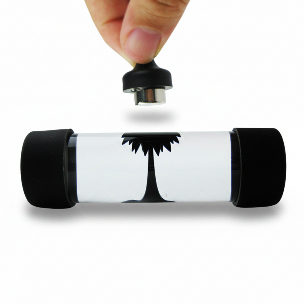 A hand is shown holding the top cap of a clear cylindrical water bottle with black silicone ends and a black printed palm tree graphic, against a plain white background.
