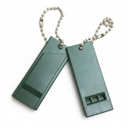 Two green whistles on a chain against a white background